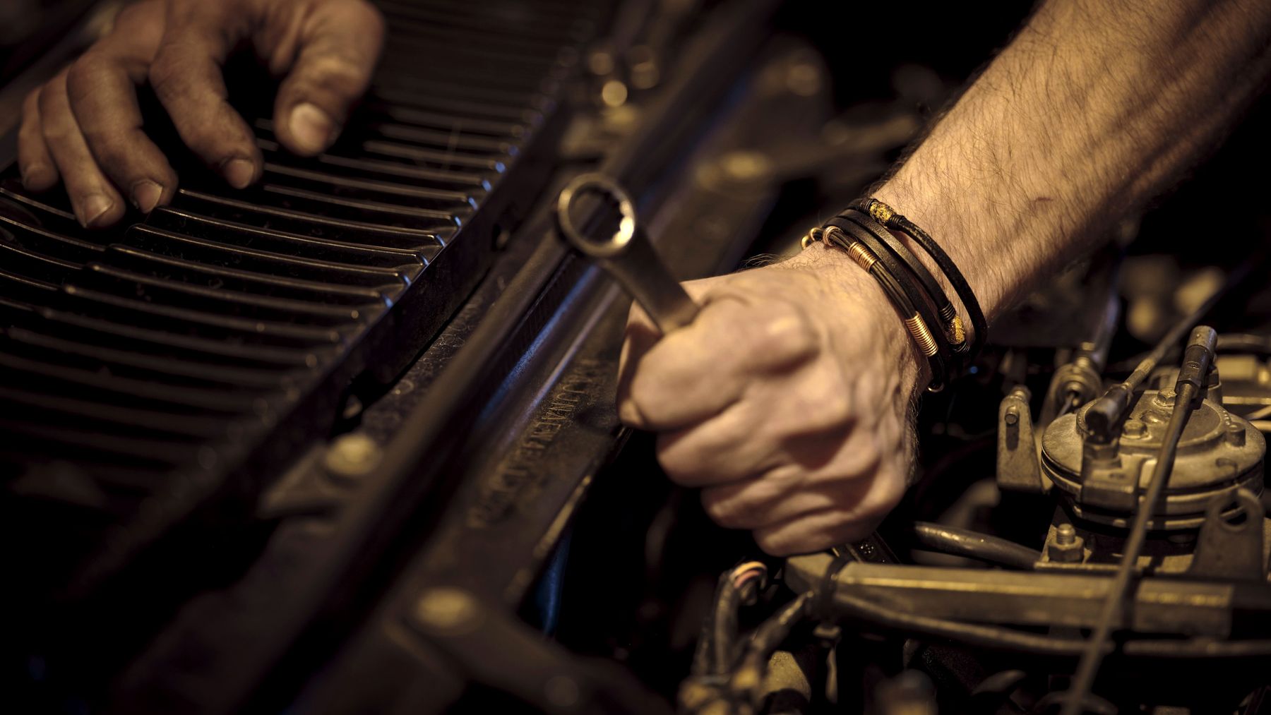 Mechanic's hands working on a car engine with a wrench